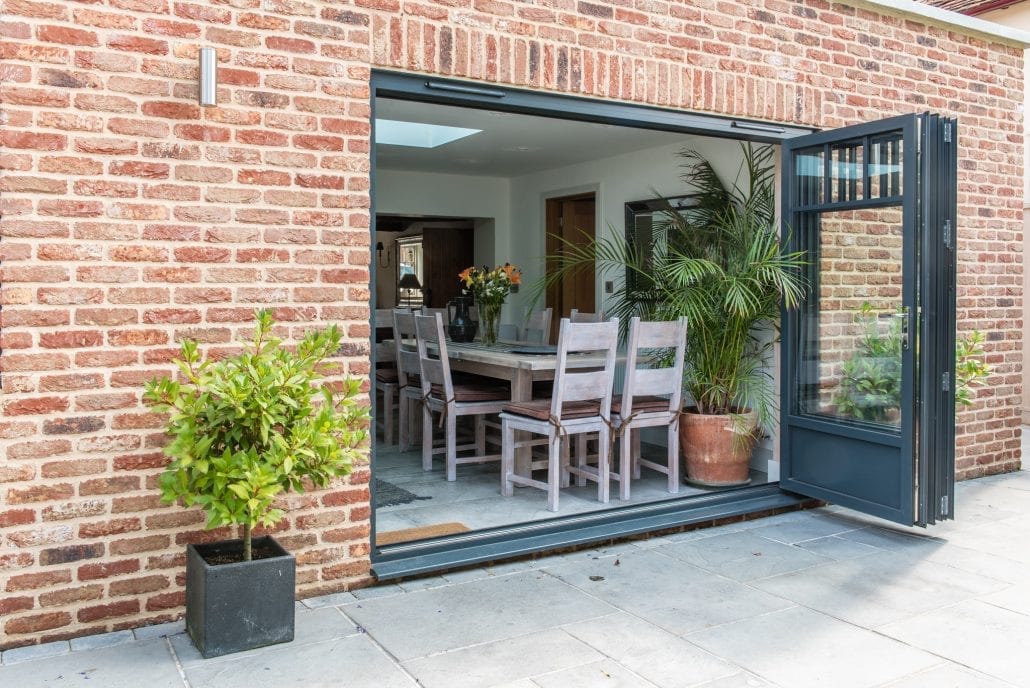 Provençal-style bifold doors framing courtyard garden, Windows Etc project