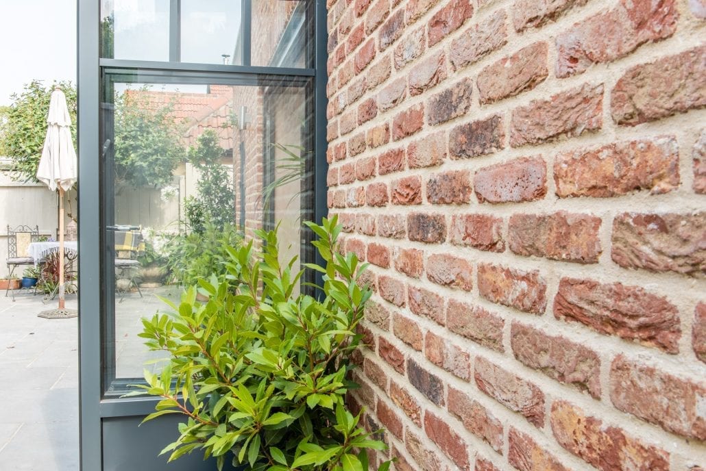 Aluminium bifold doors folded back revealing garden with lemon tree and olives