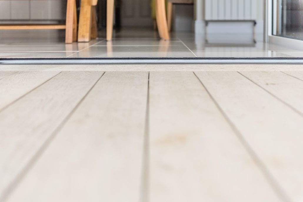 Aluminium bifold doors fully open connecting interior to limed oak deck
