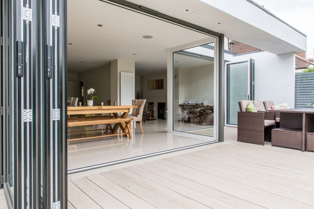Aluminium bifold doors open onto a limed oak deck at the rear of a Victorian end terrace extension