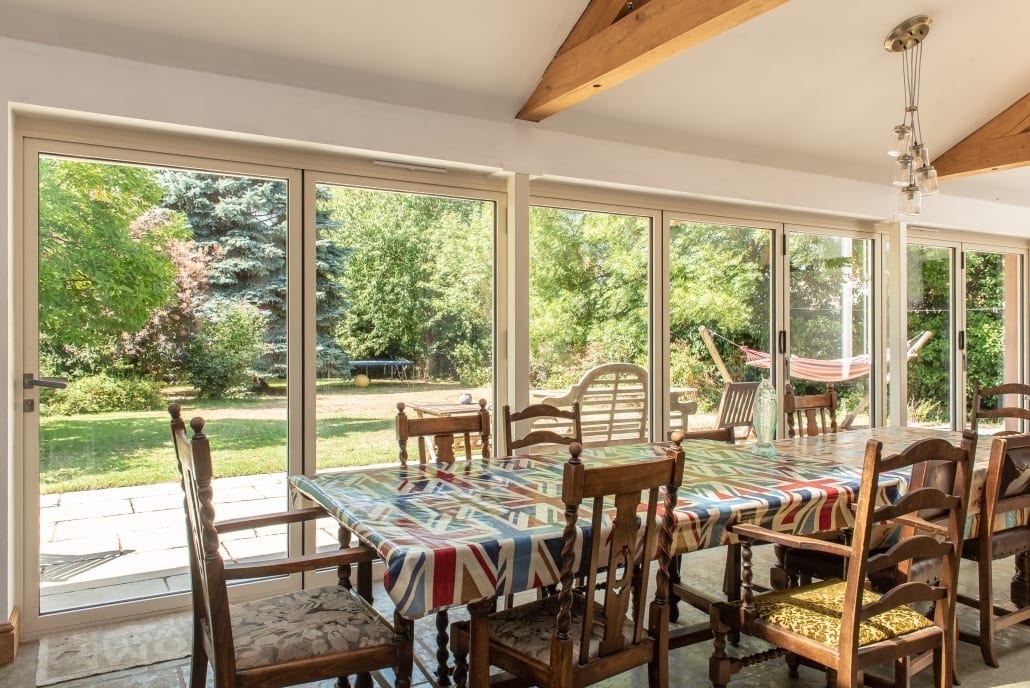 Aluminium bifold doors fully open on a rear extension, connecting kitchen to garden at a South Ipswich village property