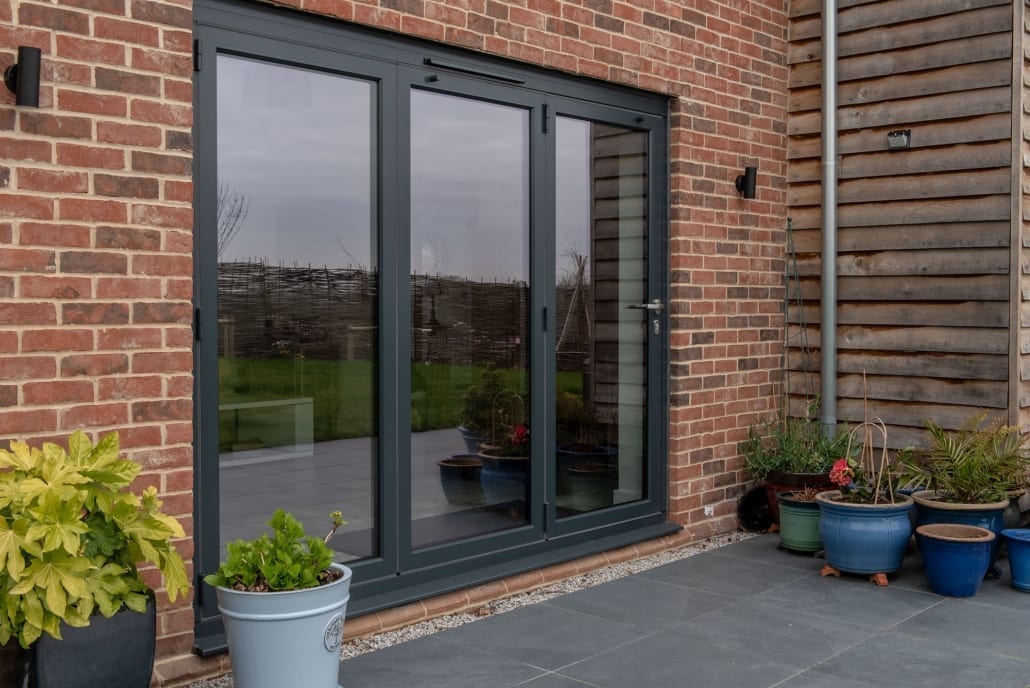 Origin aluminium window in red brick reflecting the garden