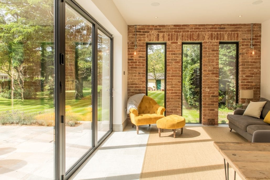 Black aluminium bifold doors open to a social garden area on a two-storey rear extension