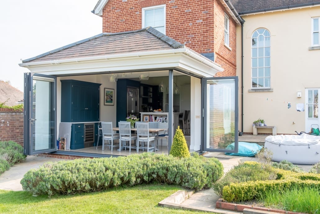 Origin offset bifold doors folded back to reveal garden access from kitchen