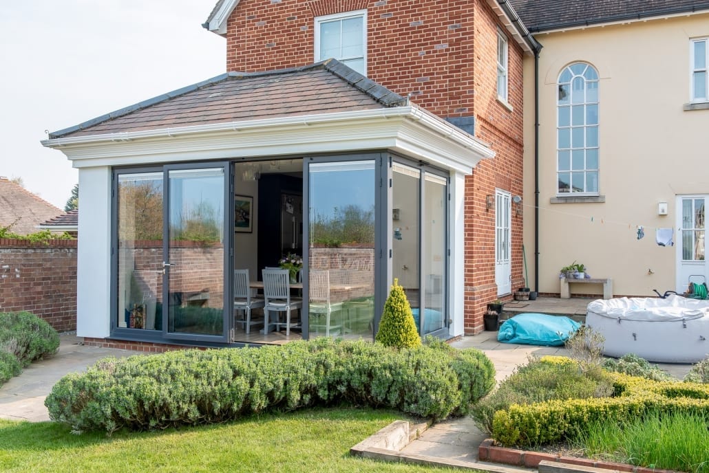 Anthracite Origin bifold doors framing a garden view from a split-level kitchen