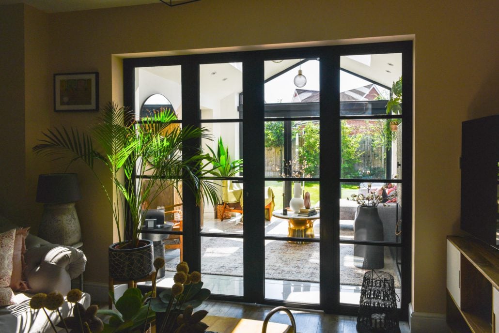 Black powder-coated aluminium Heritage 47 bifold doors and glazed extension on a contemporary home at the edge of an English heritage village