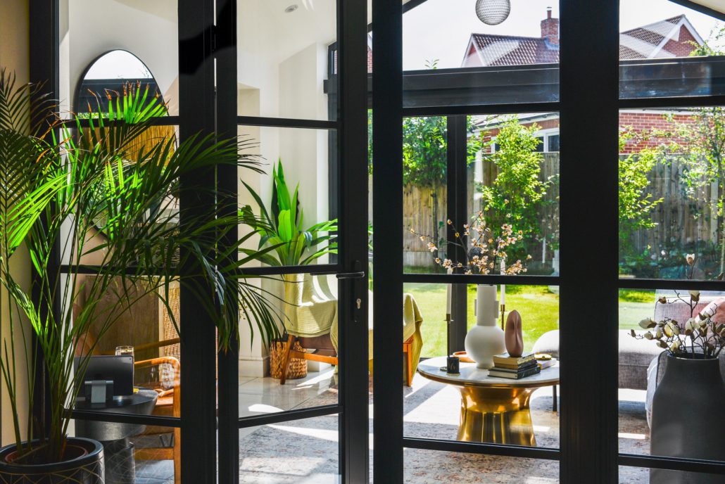 Heritage 47 aluminium bifold doors open to garden, black powder coat with flat transoms and mullions