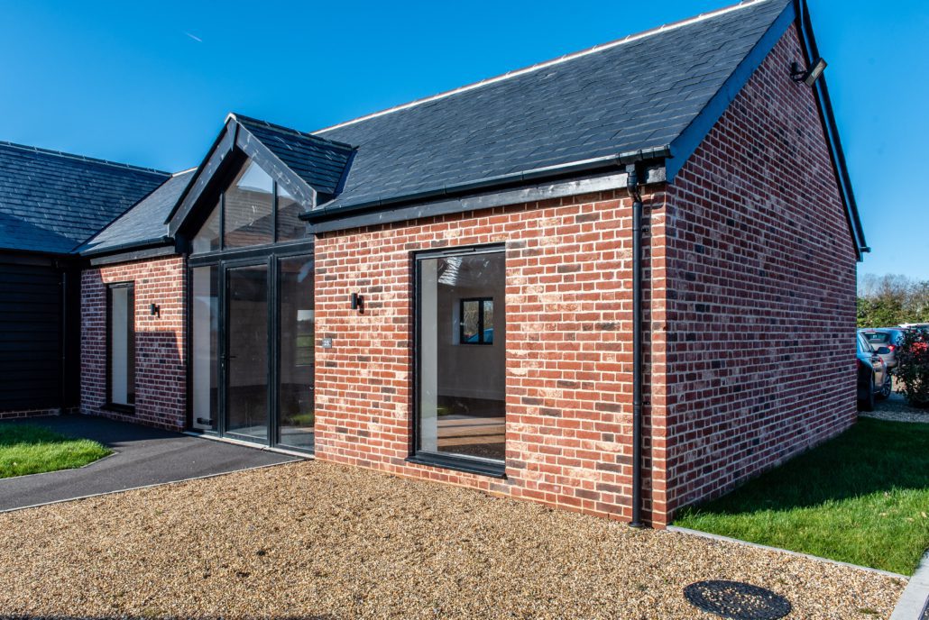 Exterior view of converted barn commercial units with black aluminium windows and bifold doors