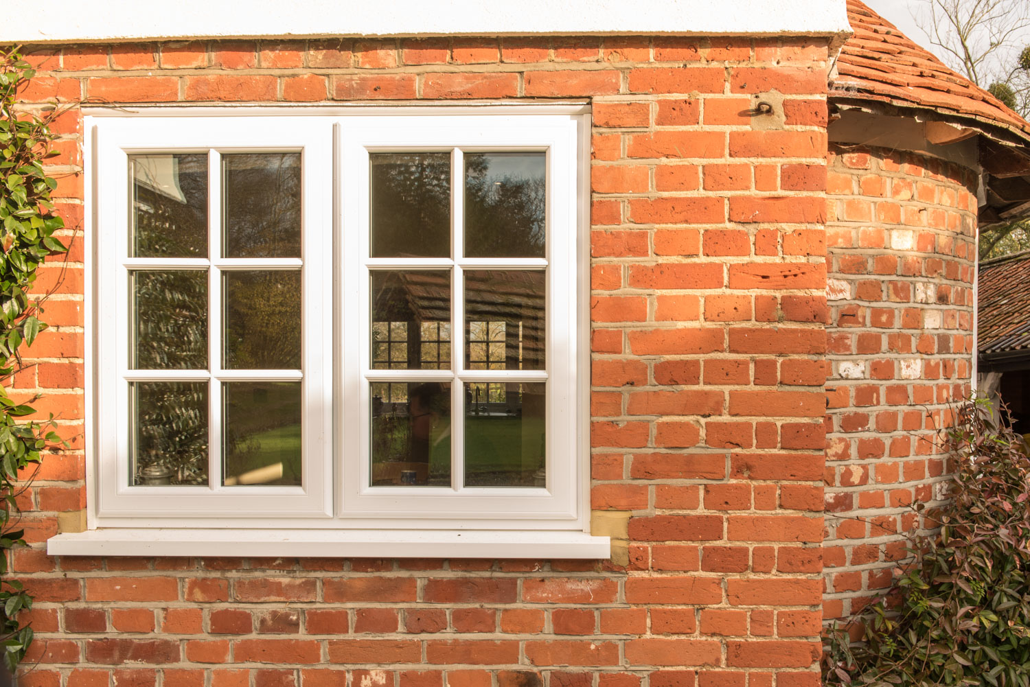 Cream uPVC casement window with astragal bars on red brick, Essex