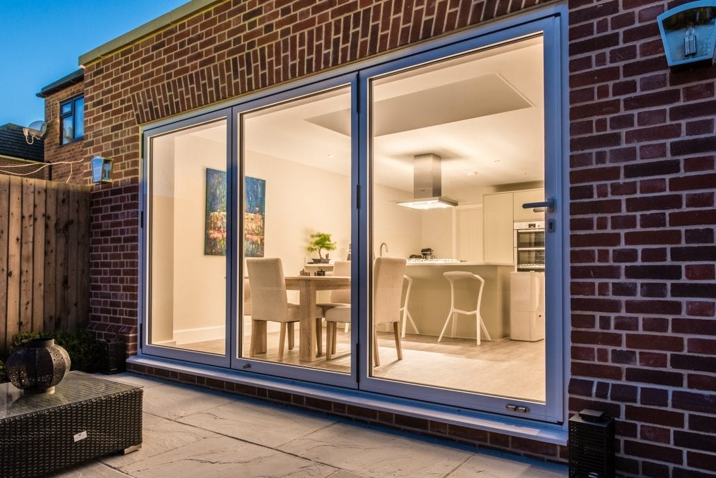 Evening view of bifold doors and flat-roof extension, Traditional and Modern project