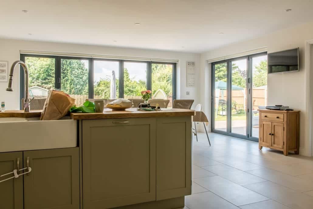 Rear elevation of rebuilt home showing aluminium bi-folding doors open to garden