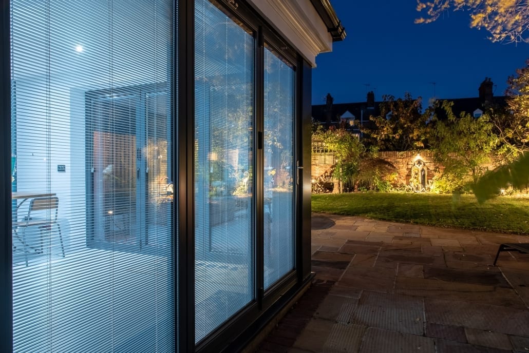 Exterior view of bifold doors and roof lantern at night, Colchester