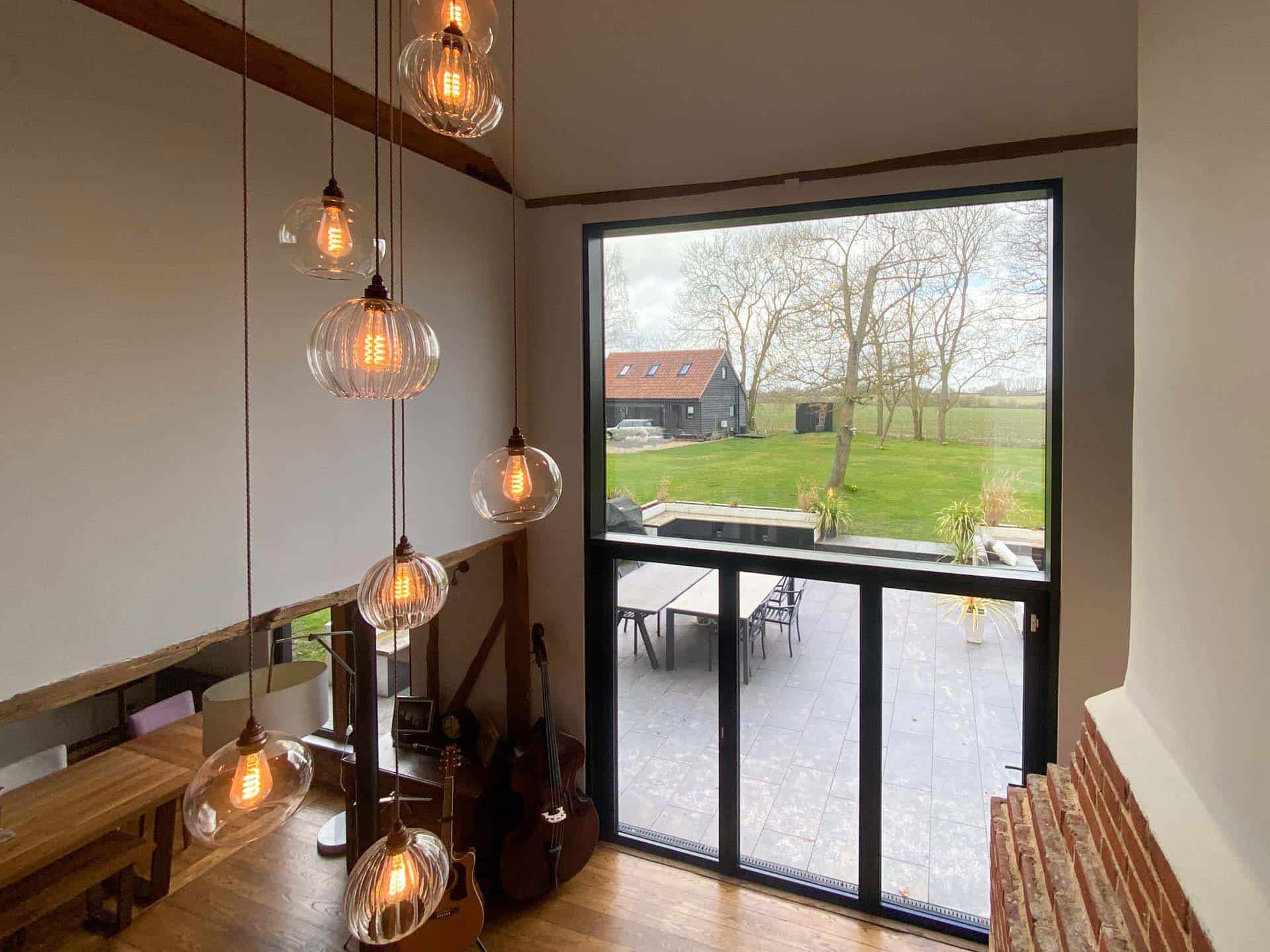Spitfire aluminium front door and Heritage 47 window in RAL 9005 Matt Black on an Essex barn conversion with dark featheredge cladding