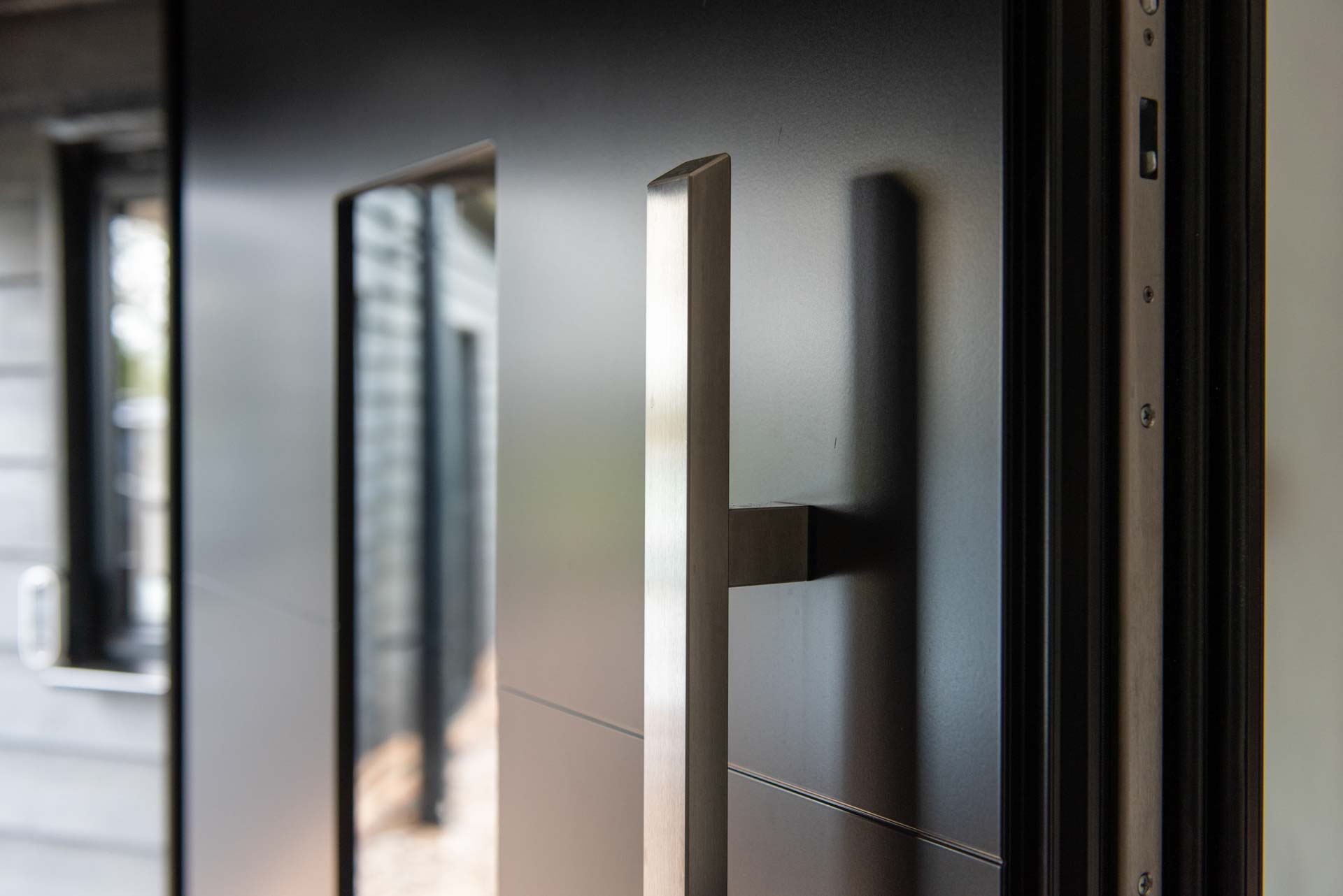 Black clad home at dusk with lit aluminium glazing, Essex