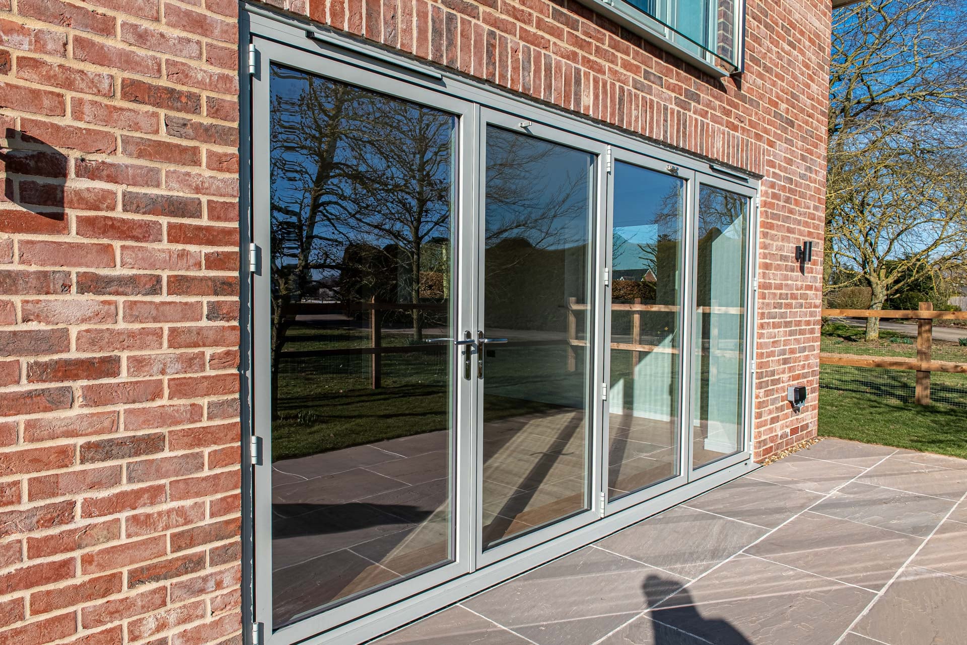 Agate grey bifold doors on red brick patio, Windows Etc Essex