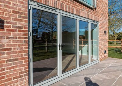 Agate grey bifold doors open onto brick patio, Windows Etc Essex
