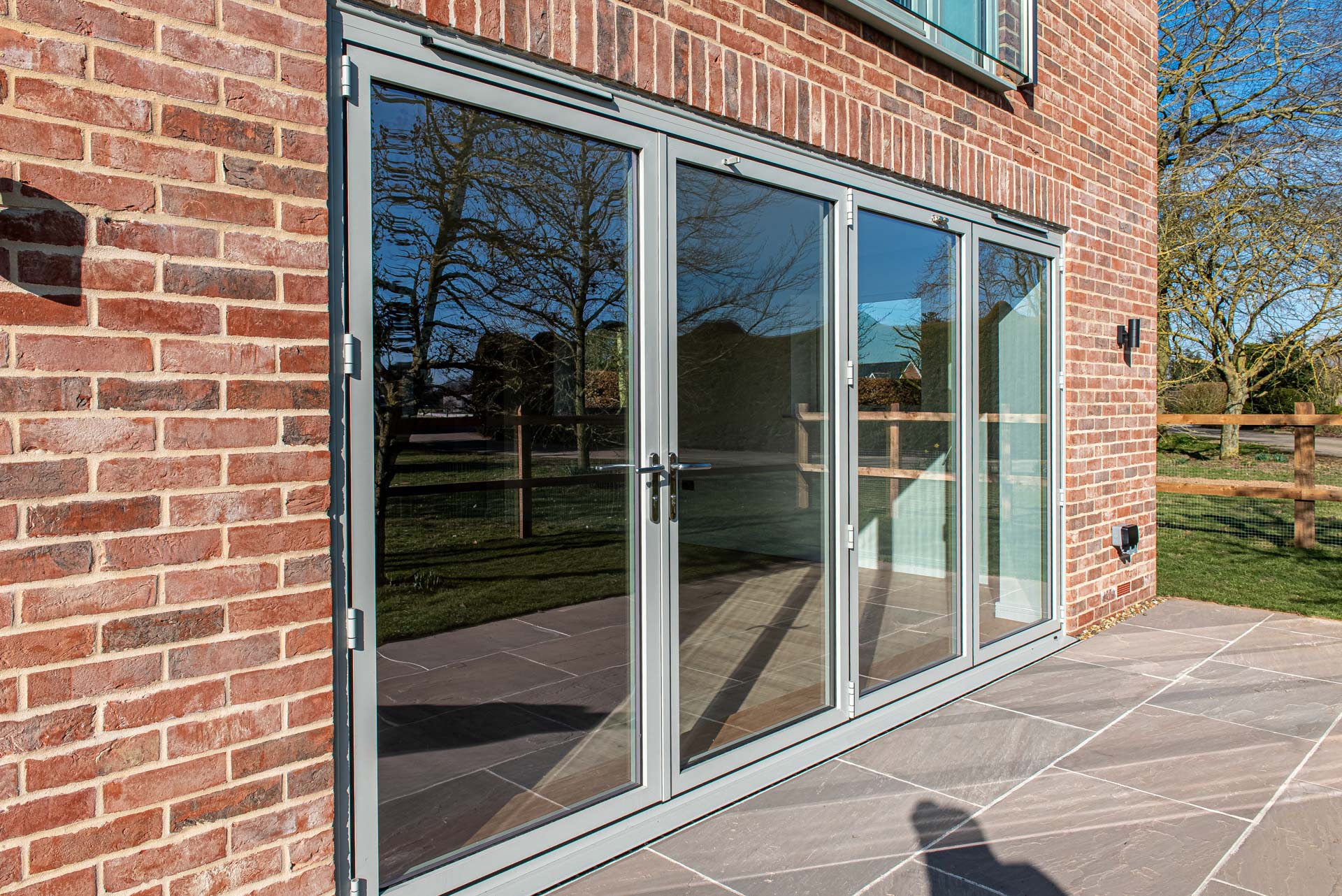 Agate grey bifold doors open onto brick patio, Windows Etc Essex