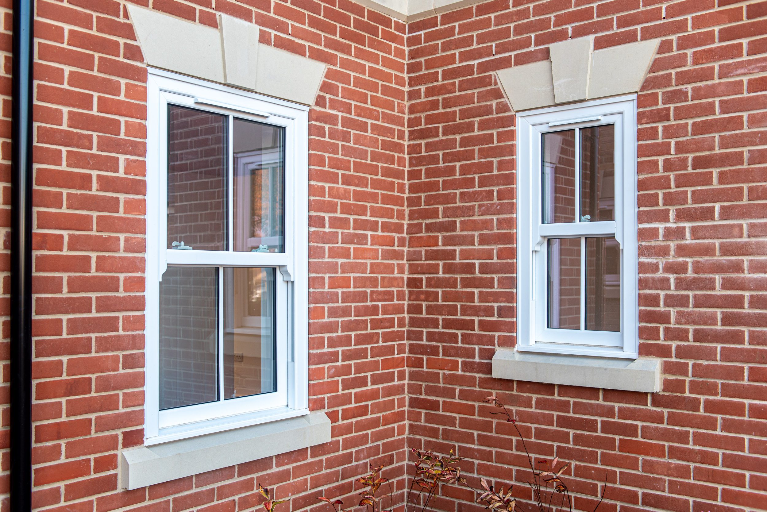 White uPVC sliding sash windows on red brick corner, Windows Etc Essex