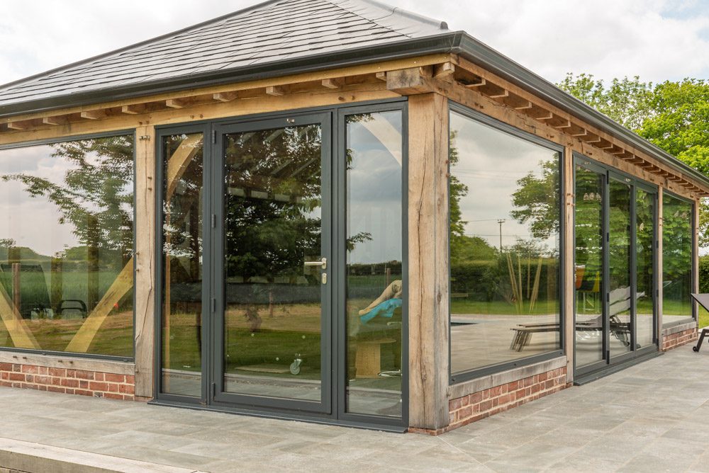 Close-up of aluminium bifold door frame and green oak junction
