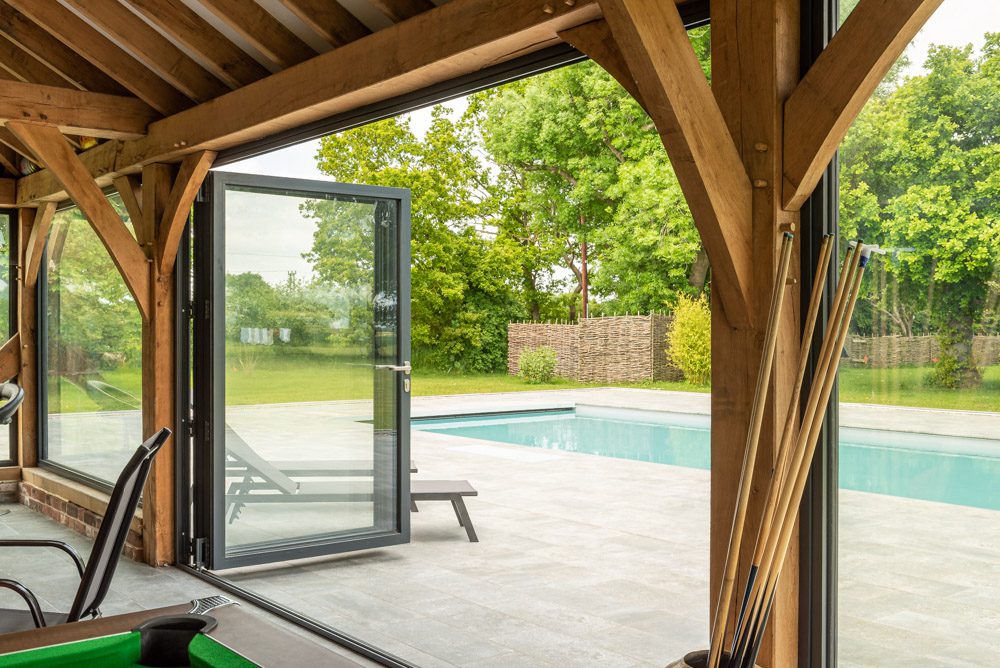 Pool house aluminium glazing, wide bifold doors with traffic door