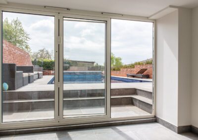White aluminium sliding doors beside pool, Windows Etc Essex