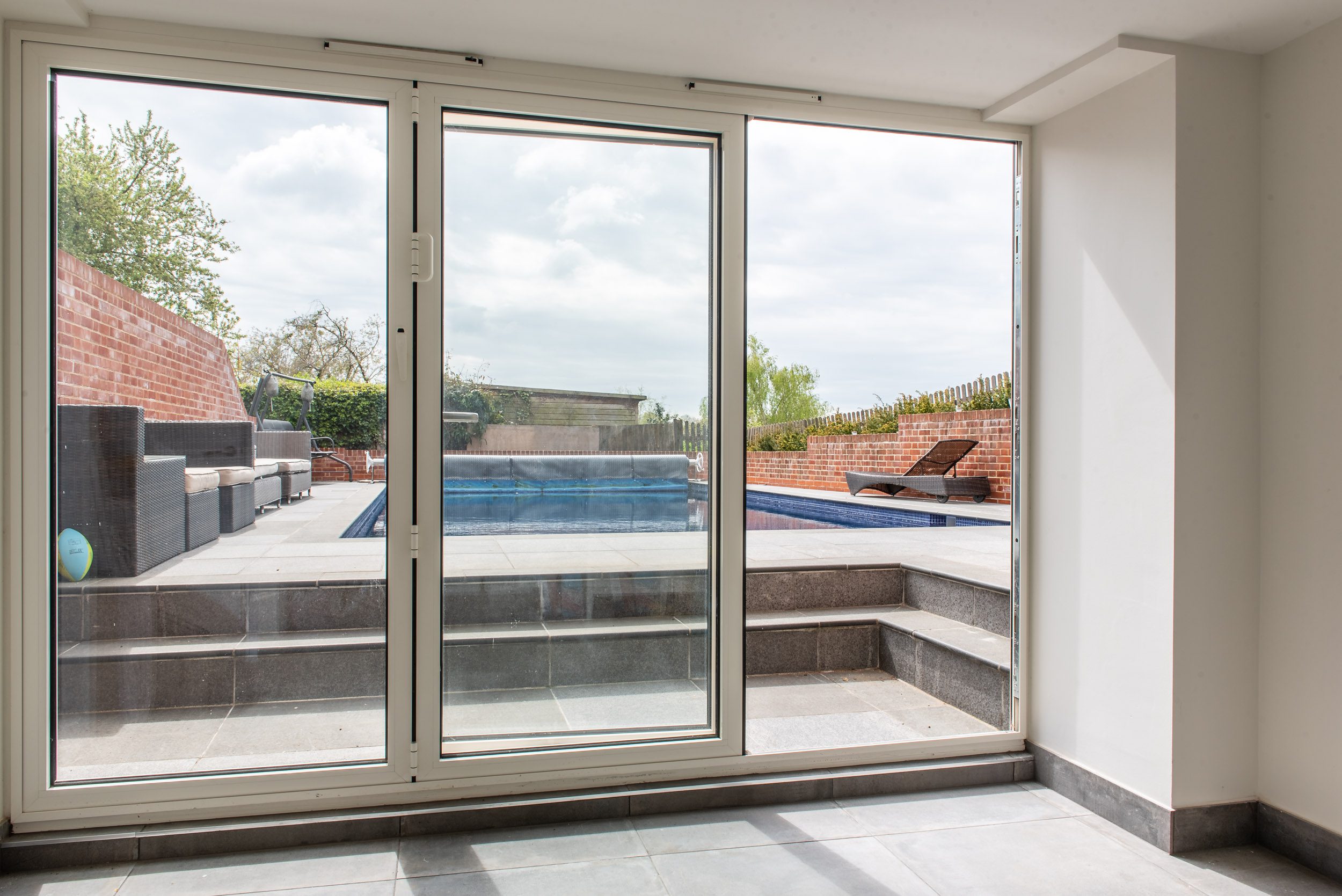 White aluminium sliding doors beside pool, Windows Etc Essex
