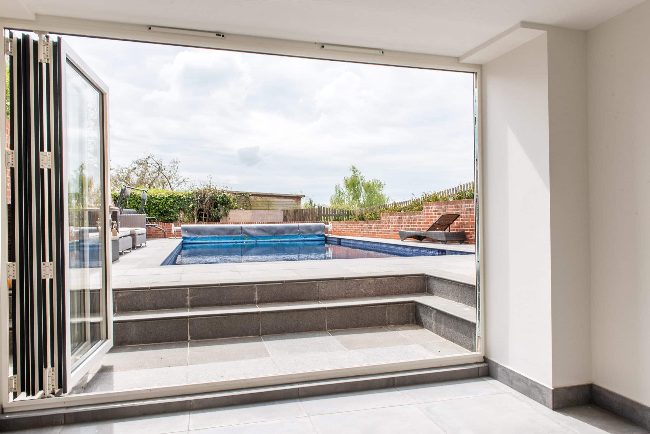 Smarts aluminium bifold doors open onto pool terrace, Windows Etc Essex