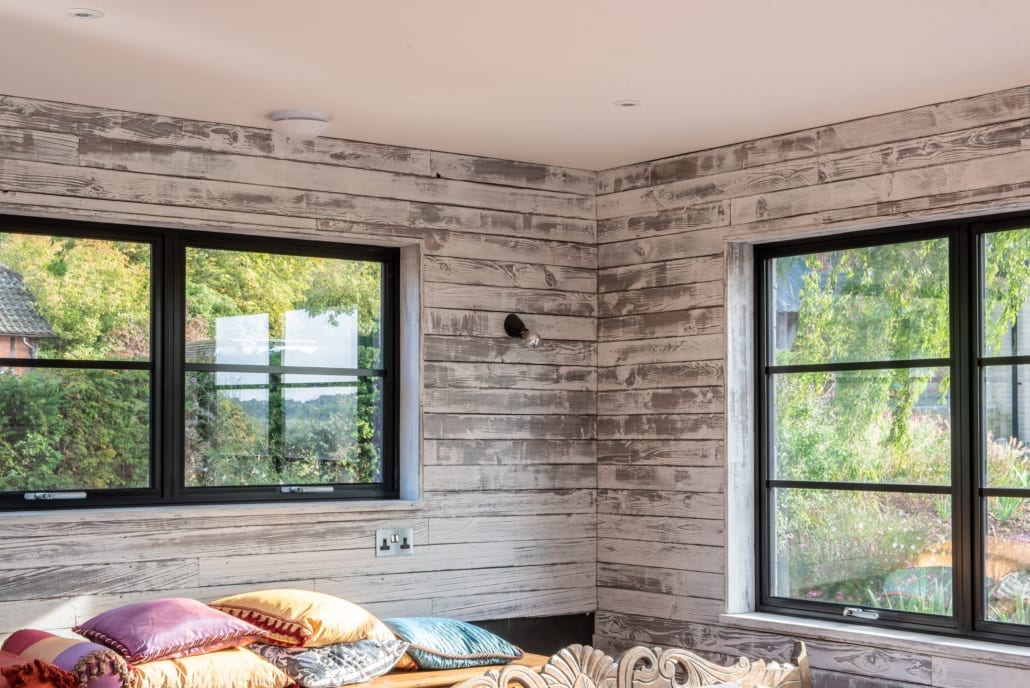 aïr bifold doors with face-fixed astragal bars on a scorched timber clad pool house overlooking a bucolic valley