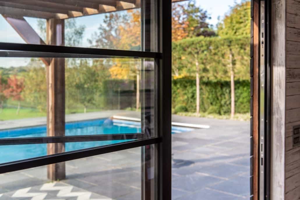 Pool house bifold doors with face-fixed astragal bars, Scandinavian aesthetic