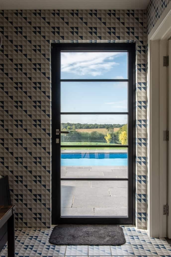 Portrait view of aïr bifold doors with astragal bars on dark scorched timber pool house