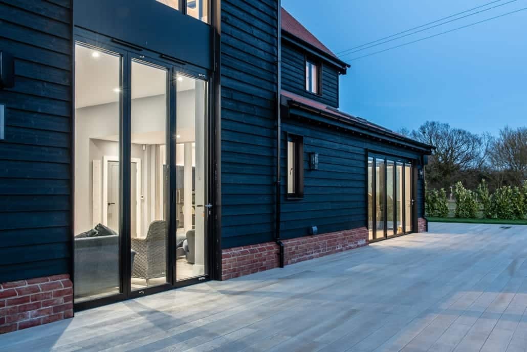 aïr bifold doors open on Essex barn new-build at night