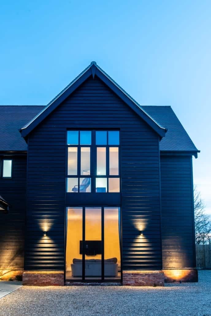 Full-height glazing on first floor of Essex barn new-build at night