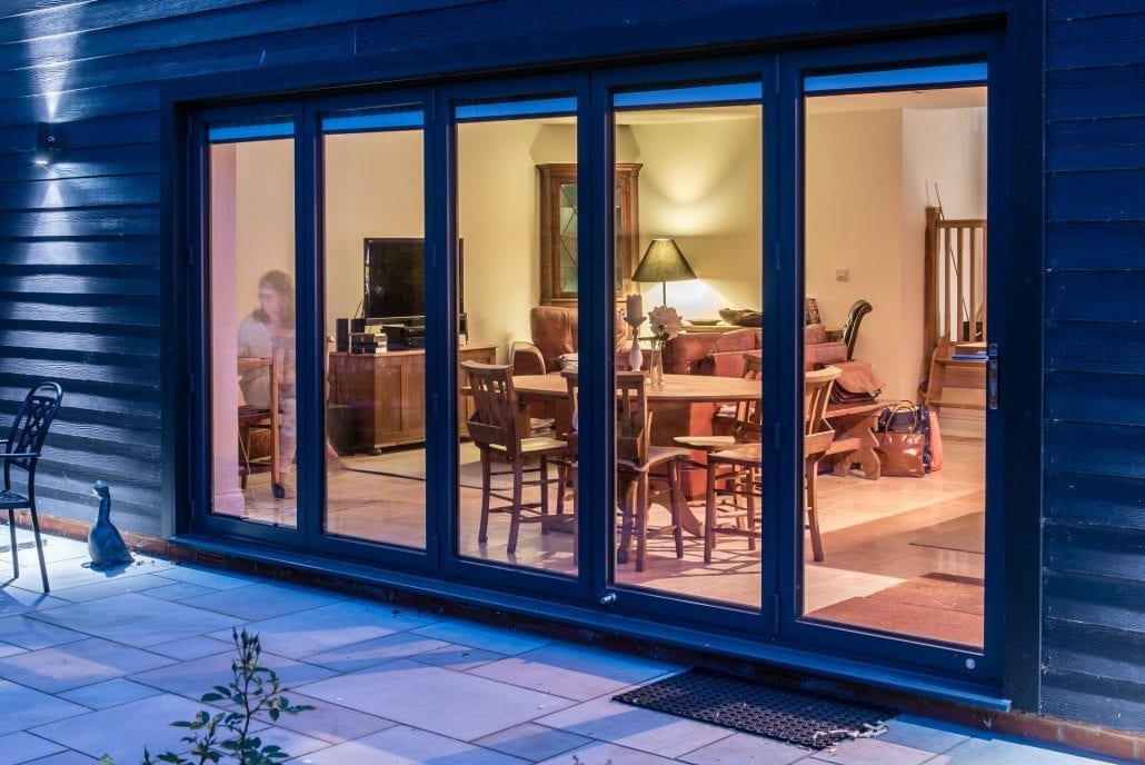 Evening exterior view of coastal chalet with dark grey aluminium glazing
