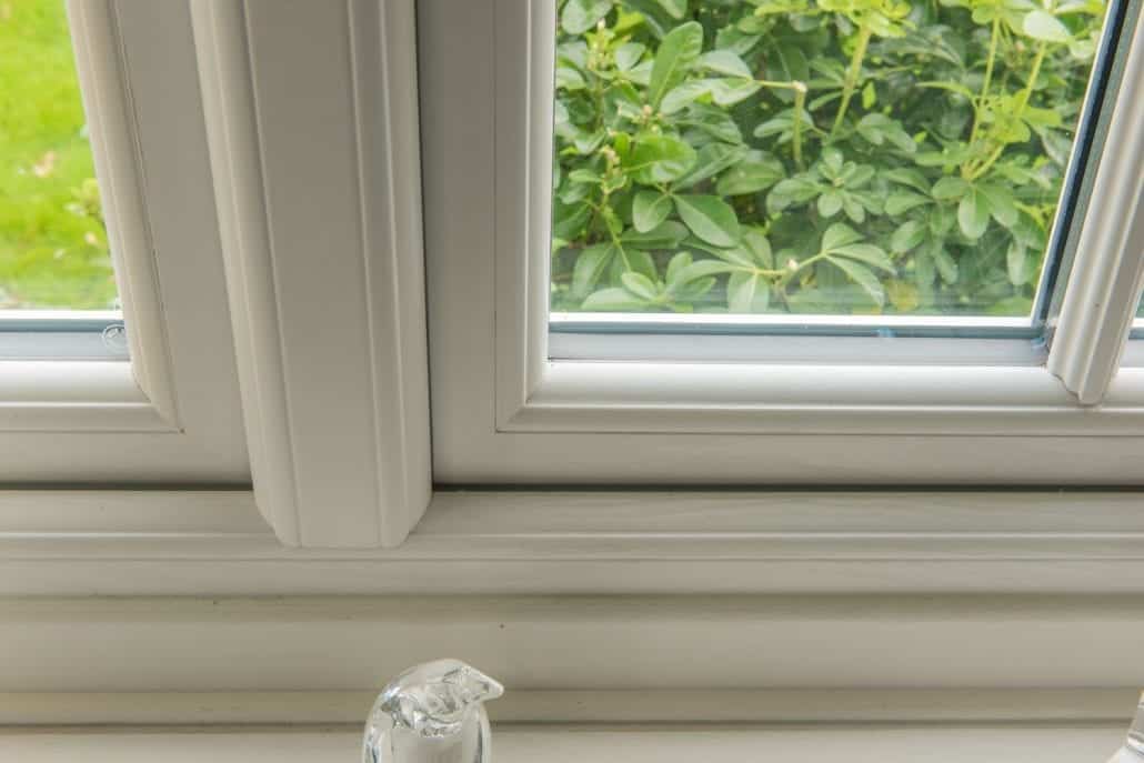 Close-up of timber-effect uPVC window profile and monkey-tail handle on rural English property