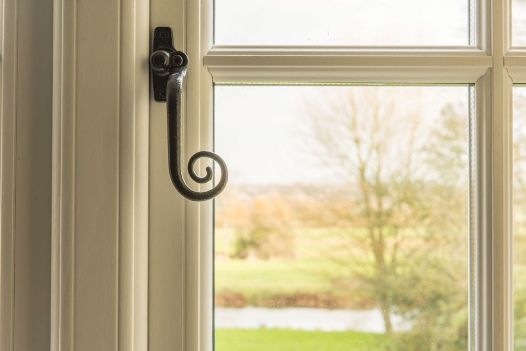 Traditional uPVC stormproof windows with monkey-tail handles on rural English farmhouse