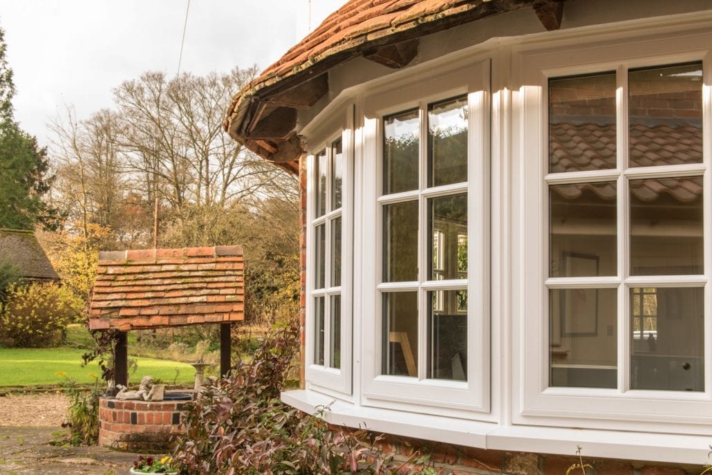 White uPVC bay window with Georgian bars on a tiled-roof cottage