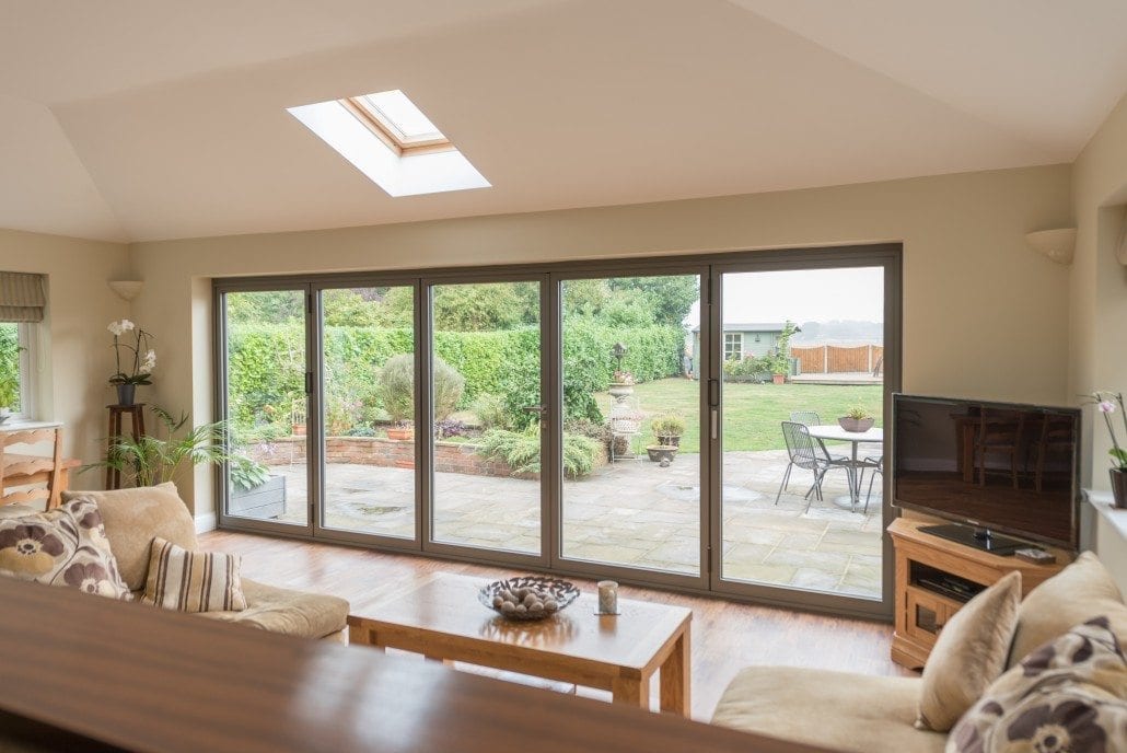 Living room with aluminium bifold doors onto a patio and garden
