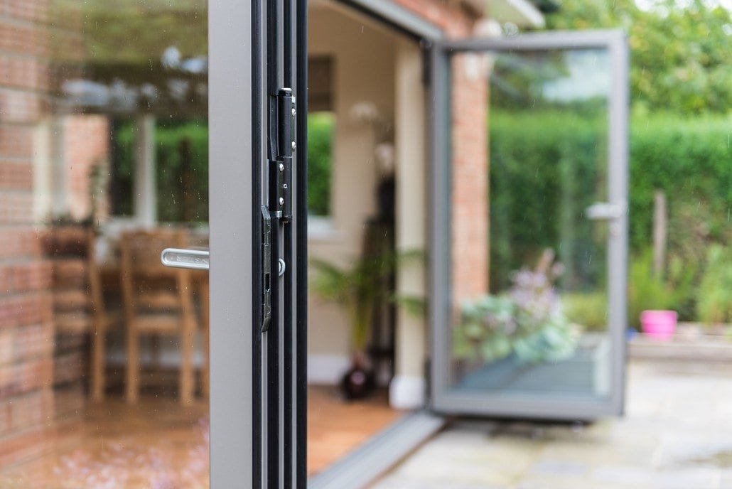 Aluminium bifold door open from the garden into a dining room