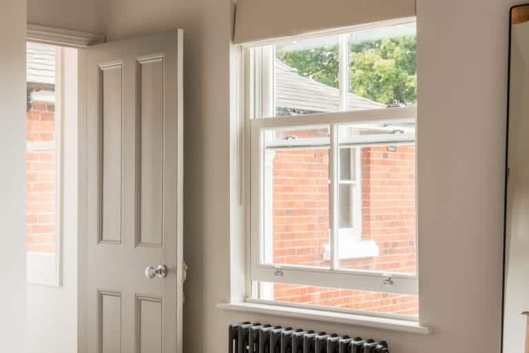White uPVC sash window beside a panelled internal door