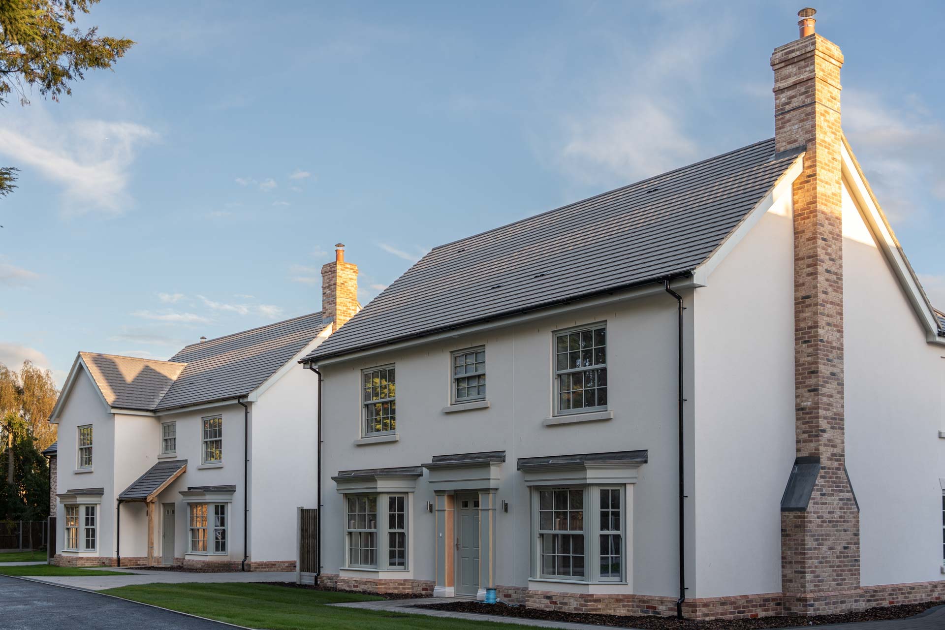 Two rendered homes at Malting Paddocks with sage uPVC vertical sliding windows and bay windows