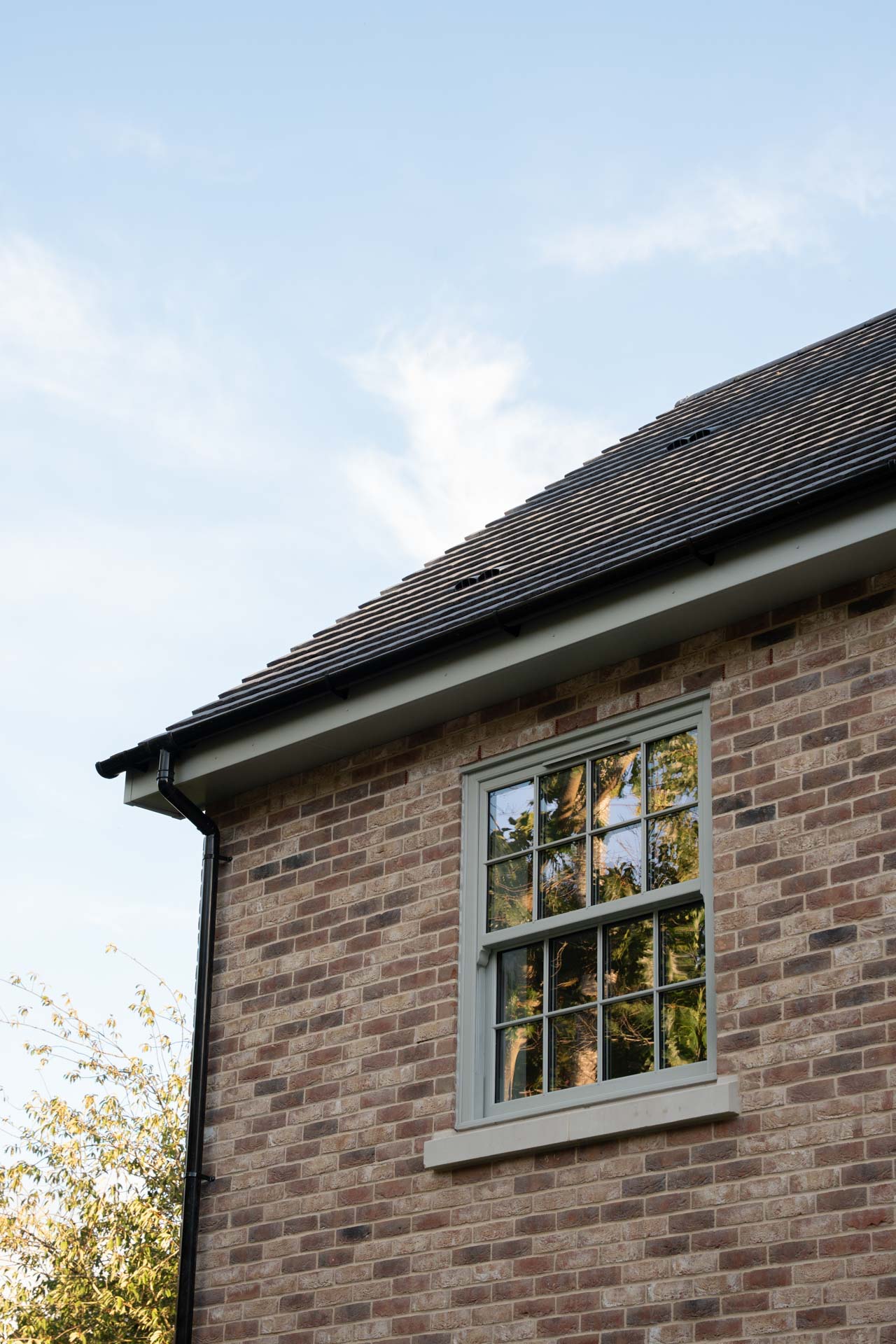 Exterior detail of a sage uPVC vertical sliding window with astragal bars against brickwork