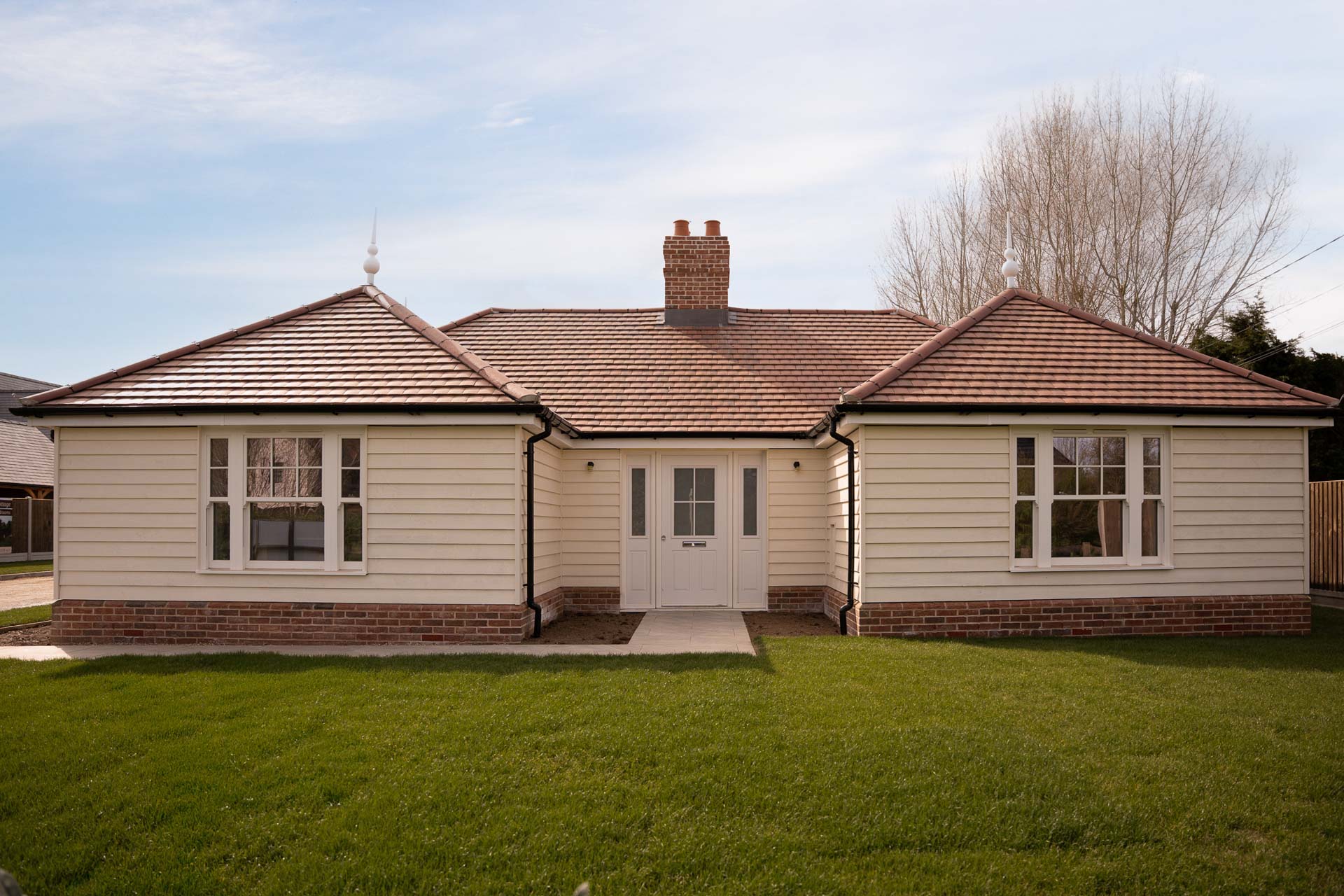 Single-storey weatherboarded home at The Nest with cream uPVC vertical sliding windows and a glazed composite front door