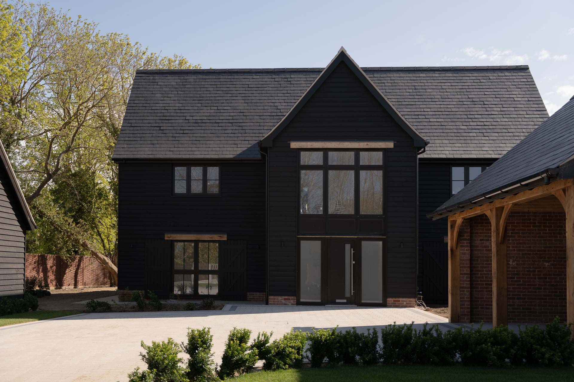 Black weatherboarded barn-style home with dark-framed windows and a full-height glazed entrance