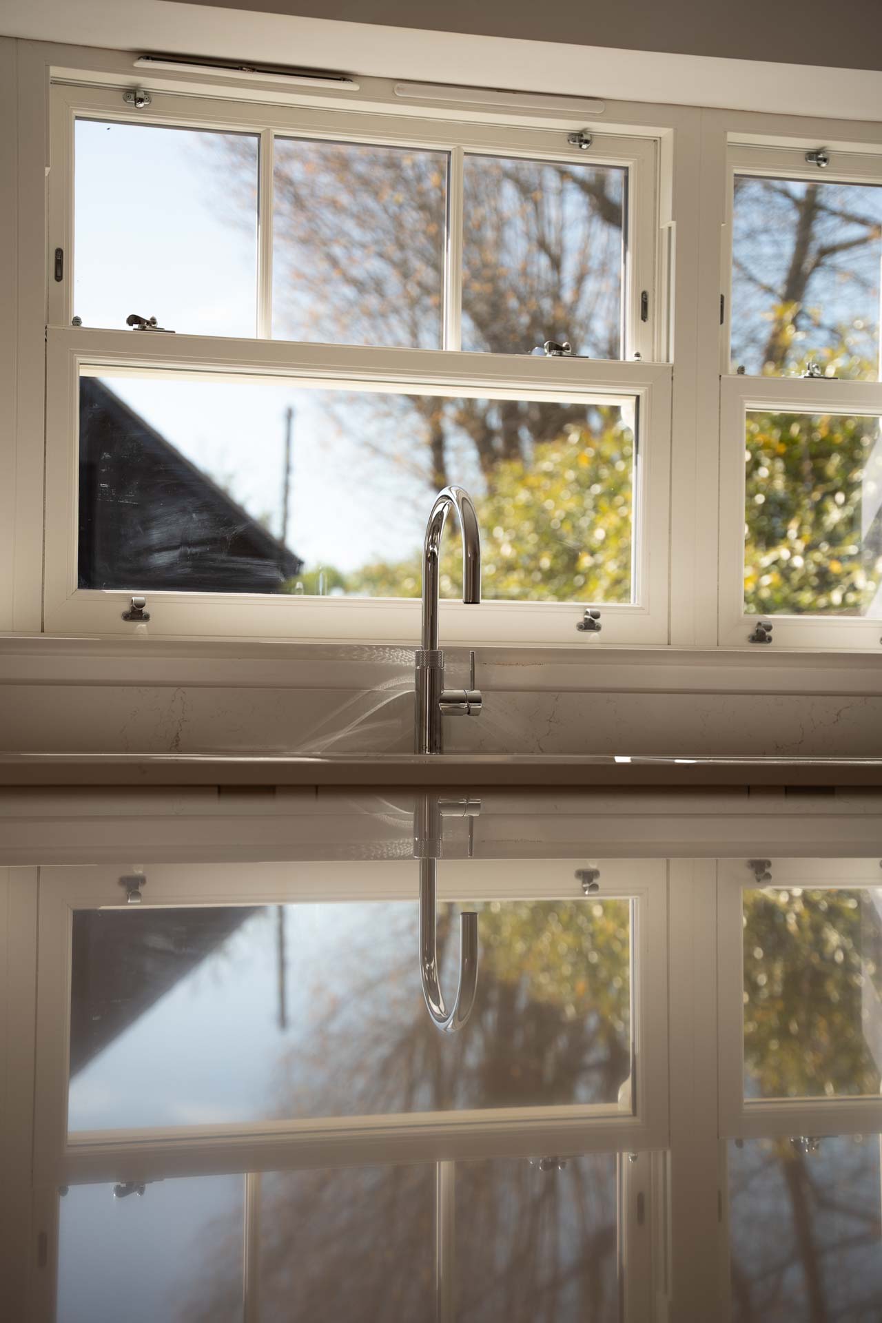 Close-up of a cream uPVC vertical sliding window above a kitchen sink, sashes open