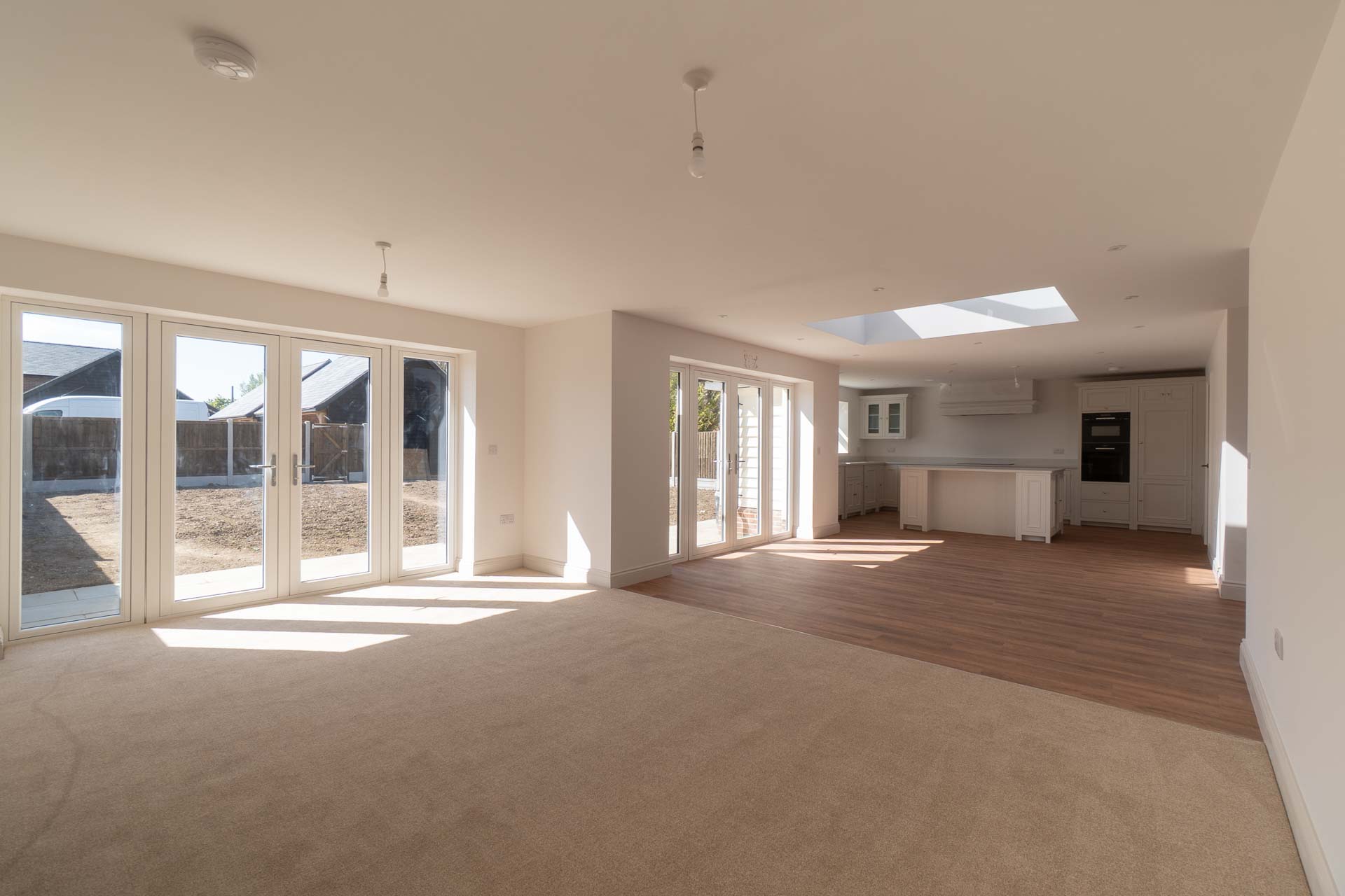 Open-plan living space with a four-panel bifold door and French doors onto the garden