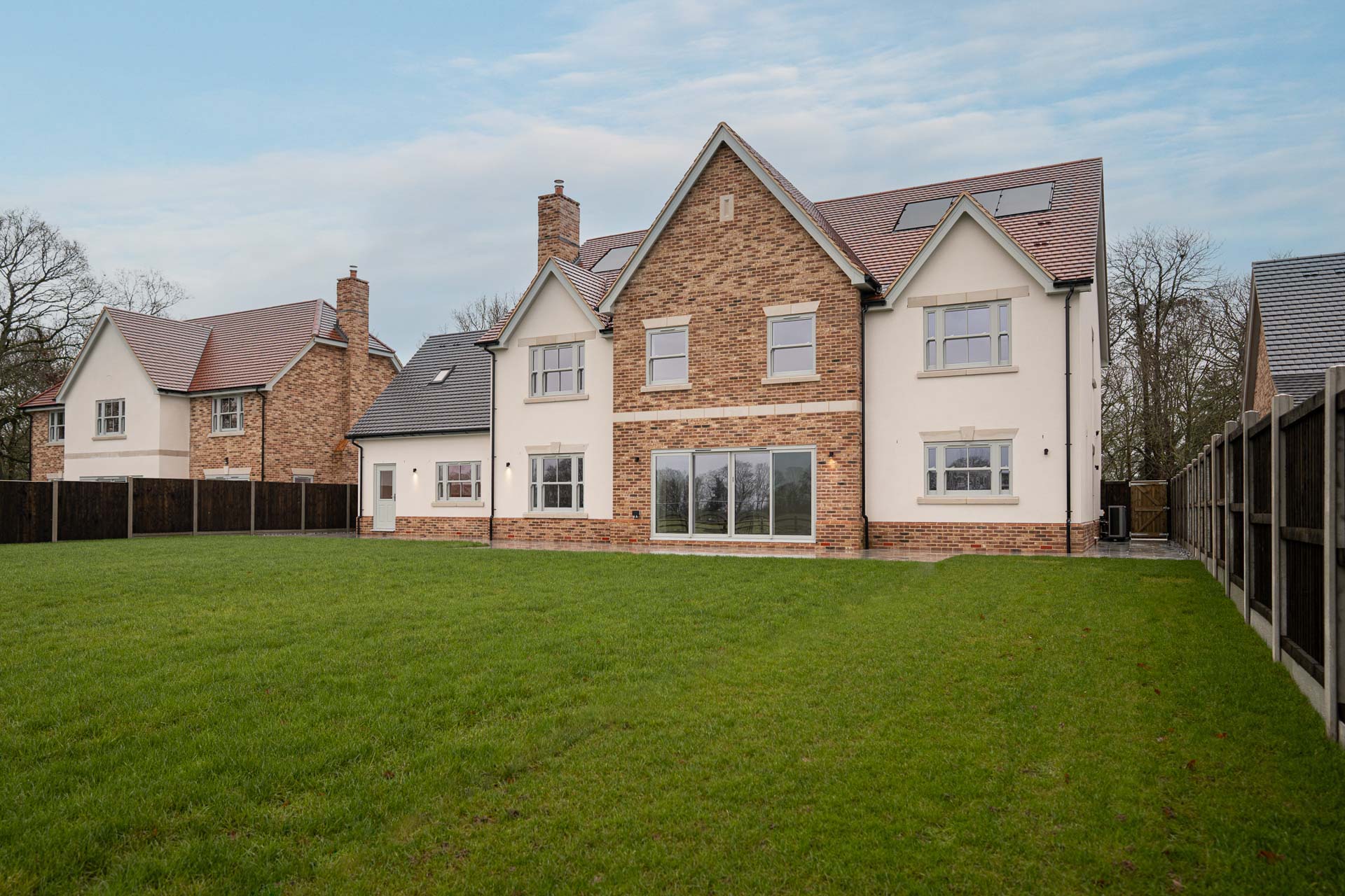 Rear elevation of a brick and rendered home at Ulting Meadows, with an aluminium sliding patio door opening onto the lawn