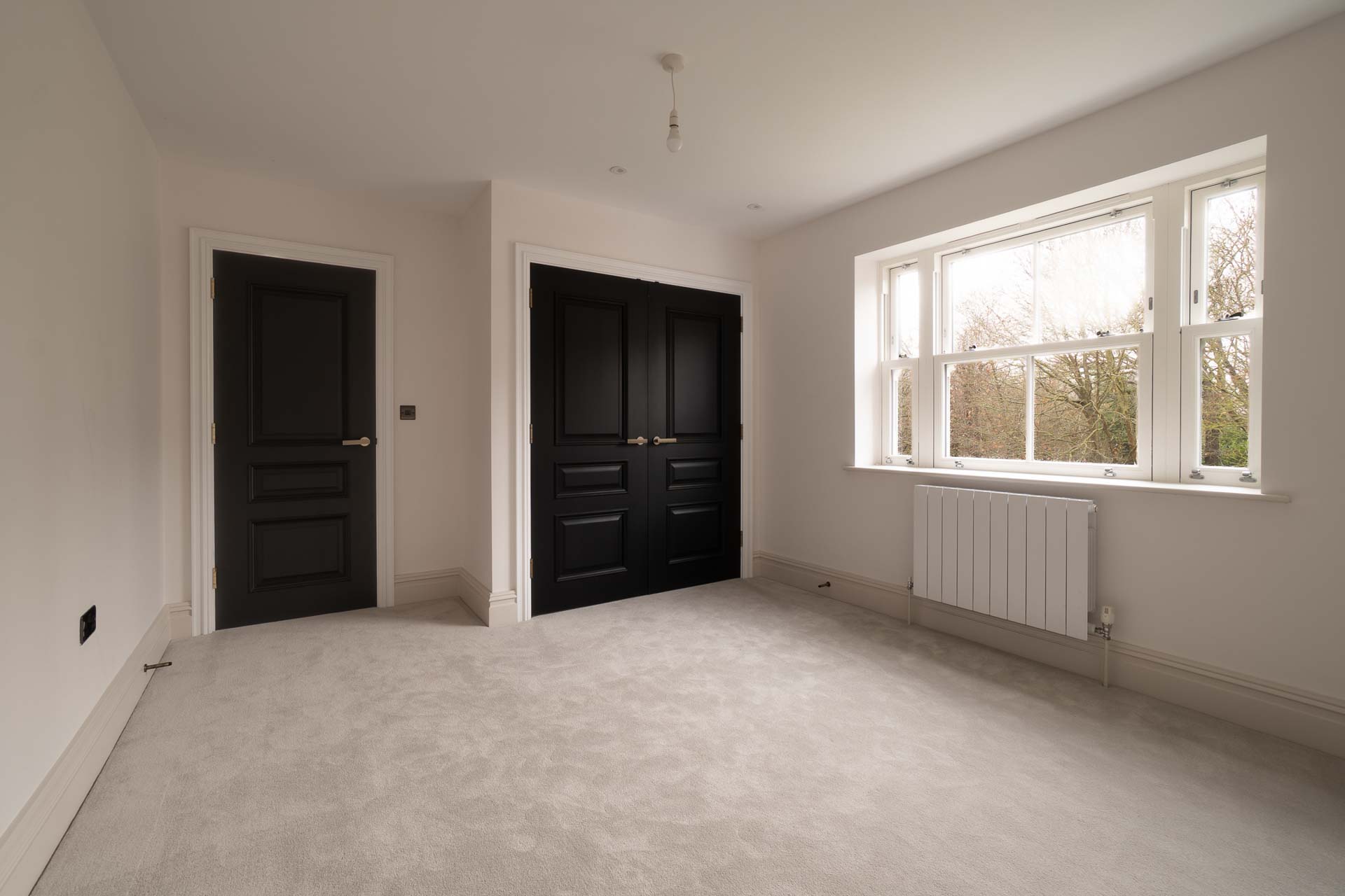 Bedroom with a three-light white uPVC vertical sliding window overlooking trees