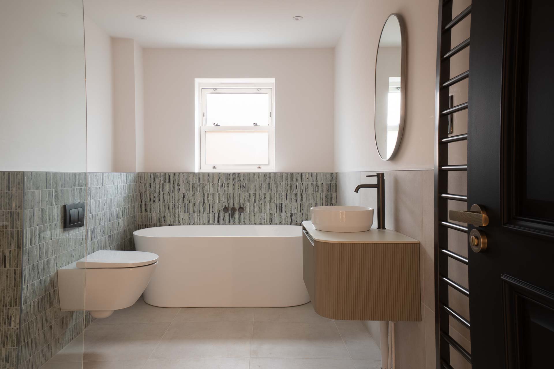 Bathroom with a white uPVC vertical sliding window above a freestanding bath
