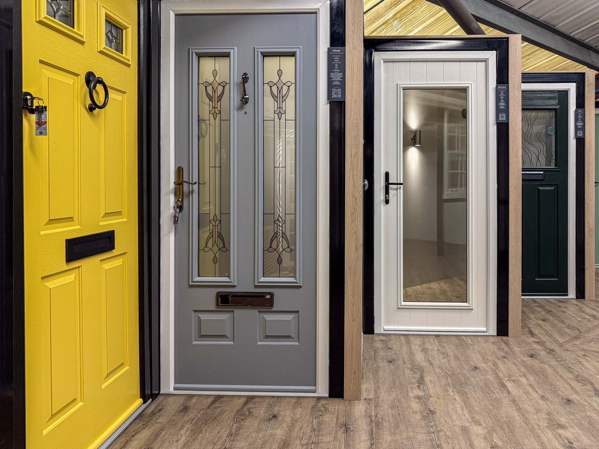 Composite front doors in yellow, grey, white and green on display in the Windows Etc showroom