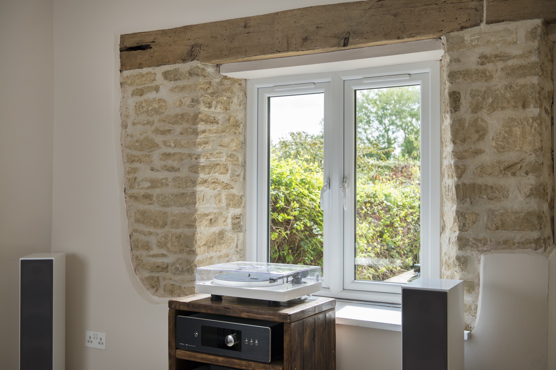 Interior view of a white Deceuninck Heritage 2800 casement window in an exposed stone wall beneath an oak beam